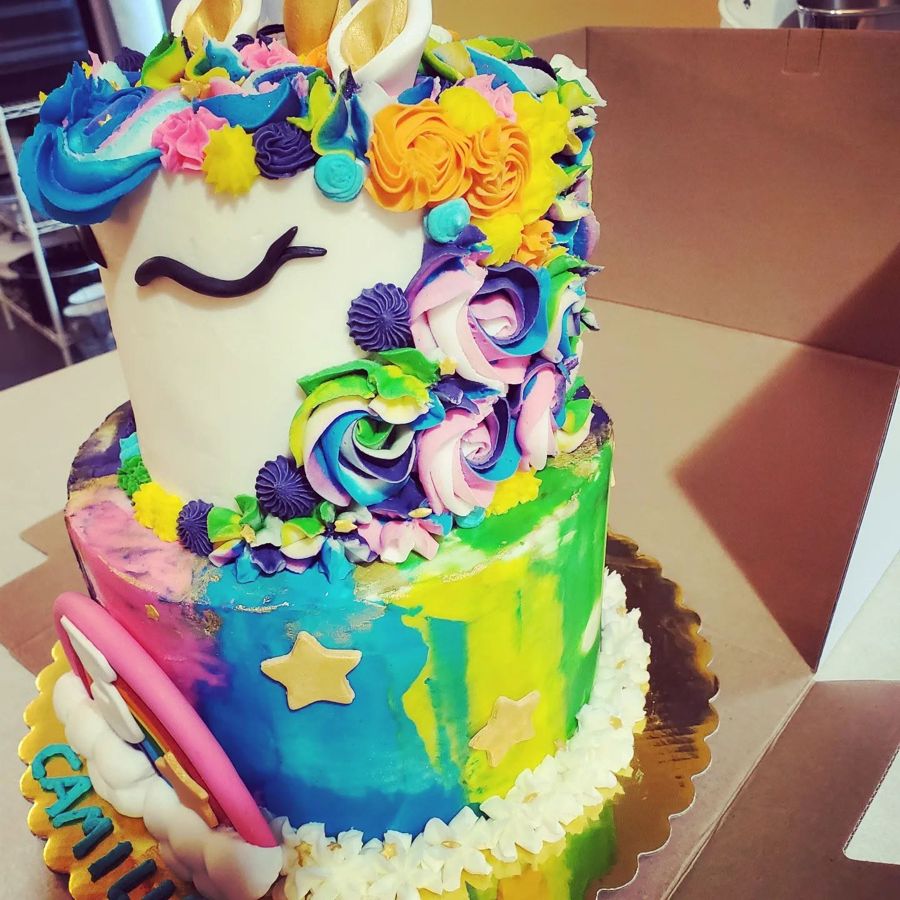 Two-tier unicorn cake with rainbow buttercream flowers and gold stars
